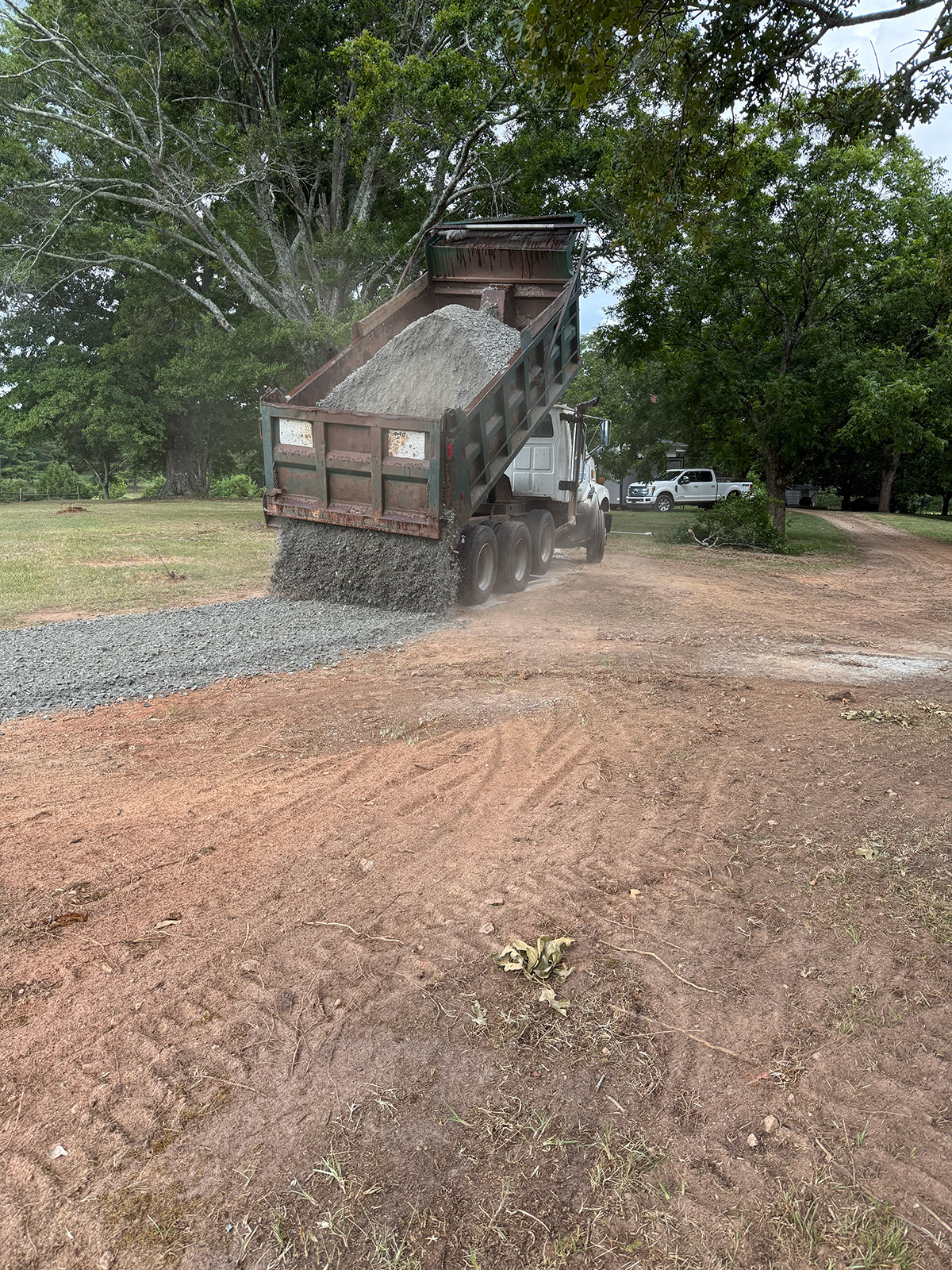 Dump truck unloading gravel for road repair.
